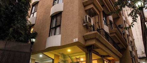 A multi-story building with balconies, air conditioning units, and potted plants.