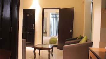 A hotel room with a bed, a sofa, a small table, and a door leading to a bathroom.