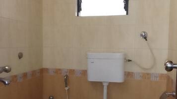 A small bathroom with a toilet, a shower, and a window.