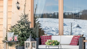 A cozy outdoor seating area with a wicker sofa, a small table, and a Christmas tree. - Villa Gorsky-Janso (Poronin)