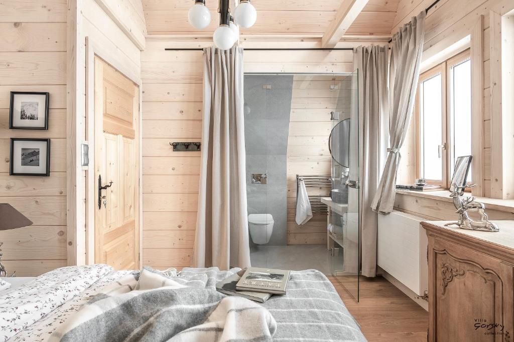 A wooden interior with a bed, a window, and a bathroom visible through an open door.