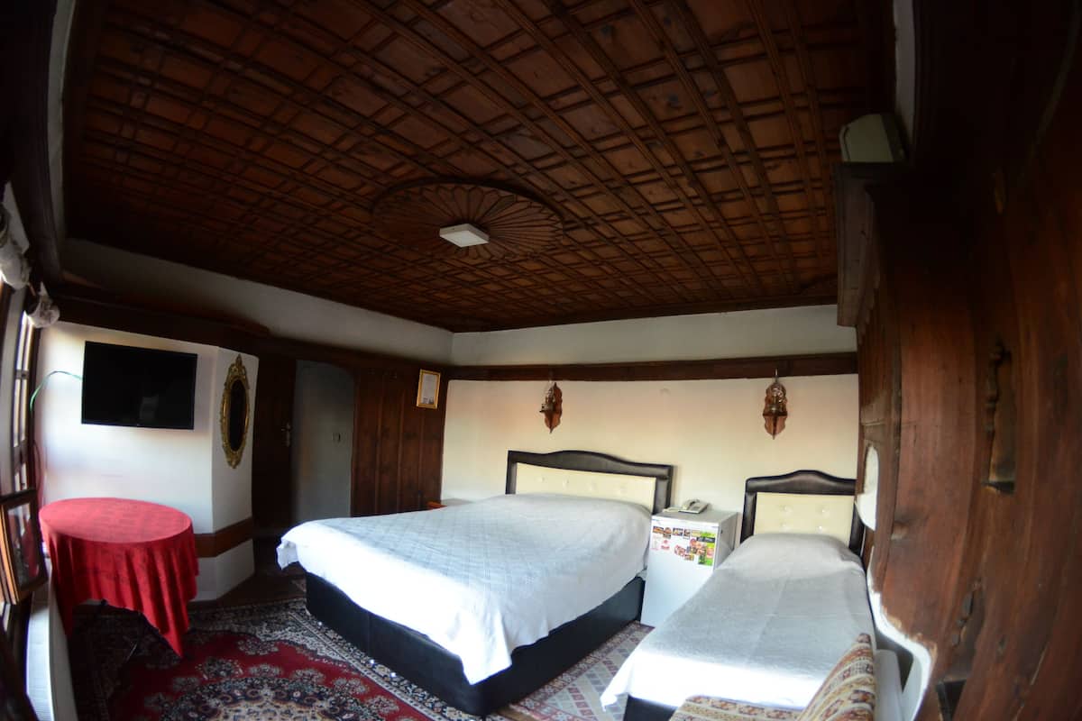 Een kamer met twee bedden, een klein tafeltje en een houten plafond.