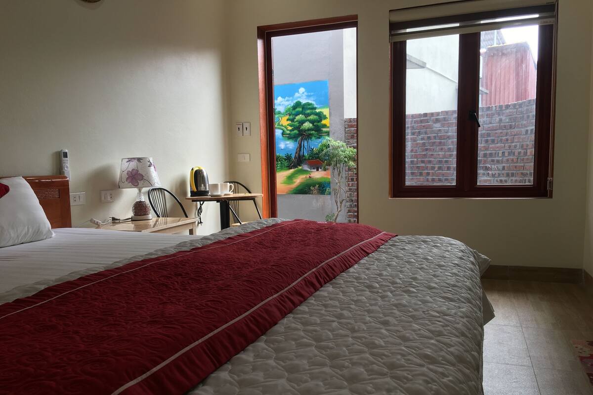 Une chambre d’hôtel avec un grand lit, un bureau avec une bouilloire, une chaise et un tableau au mur.