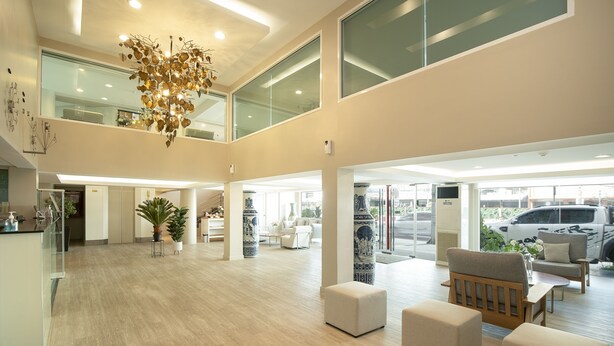 A spacious lobby with a high ceiling, large windows, and a modern chandelier. There are seating areas with ottomans and a sofa. - Bangkok Loft Inn (Bangkok)