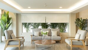 A modern living room with a sofa set, two armchairs, a coffee table, and large windows with blinds. - Bangkok Loft Inn (Bangkok)