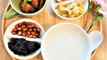 A wooden tray with various food items including a bowl of rice, a bowl of peanuts, a bowl of black fungus, a bowl of sliced sausages, a bowl of sliced boiled eggs, and a bowl of sliced potatoes.