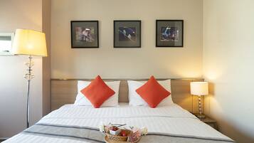 Una habitación de hotel con una cama bien hecha, una mesita de noche con una lámpara y tres cuadros en la pared.