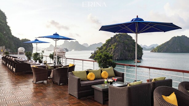 A deck with wicker furniture, blue umbrellas, and a view of the sea and islands. - Rosa Boutique Cruise (Tuan Chau)