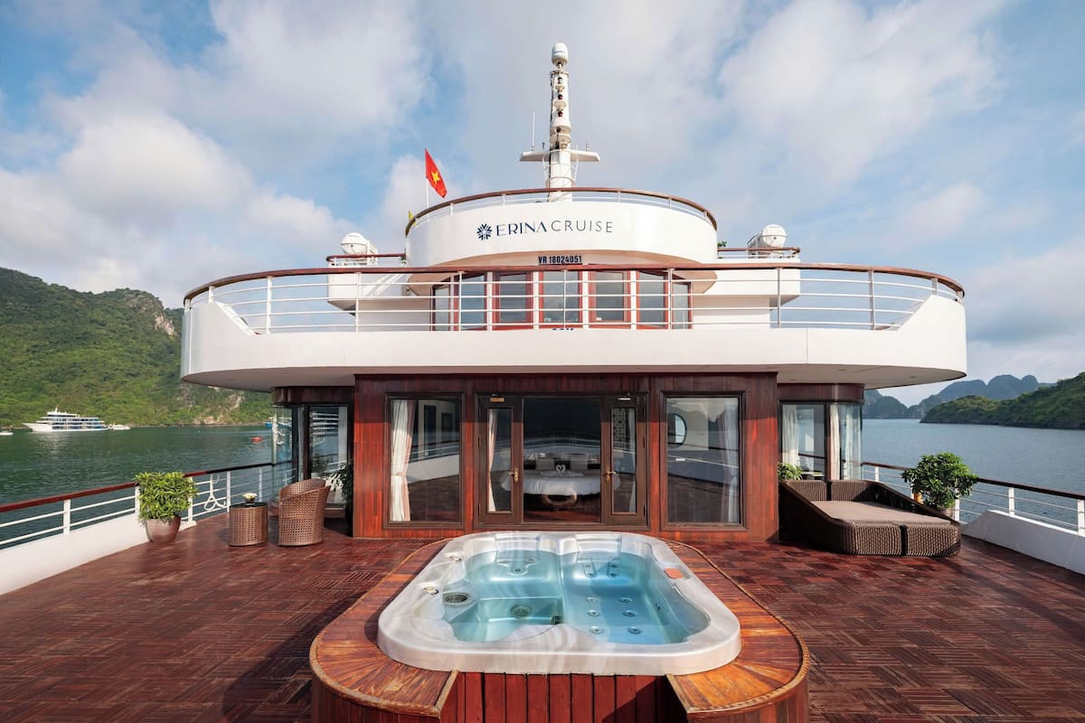 A cruise ship with a hot tub and outdoor seating area, surrounded by water and greenery.