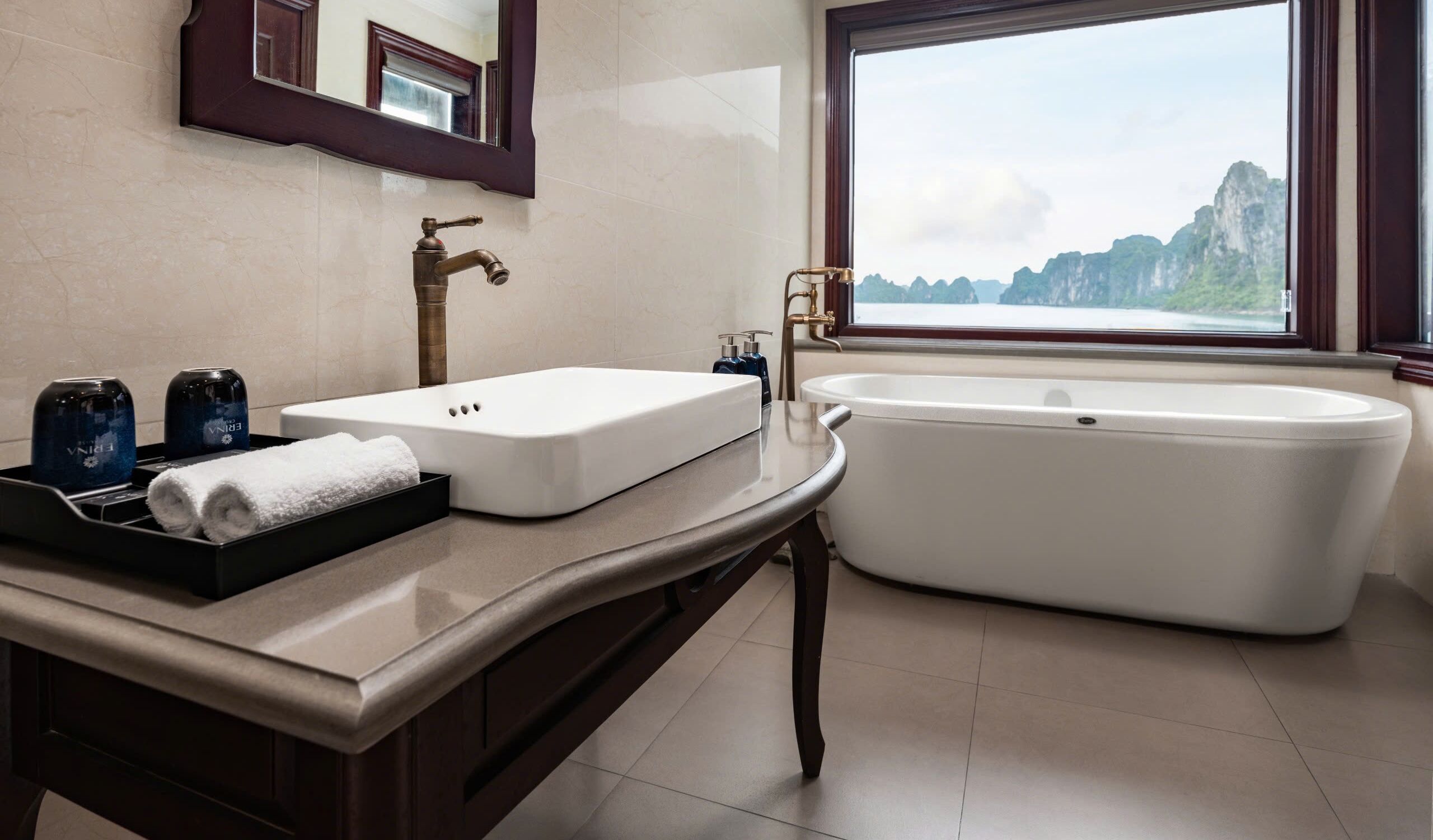 A bathroom with a white sink, a bathtub, and a window with a view of mountains.