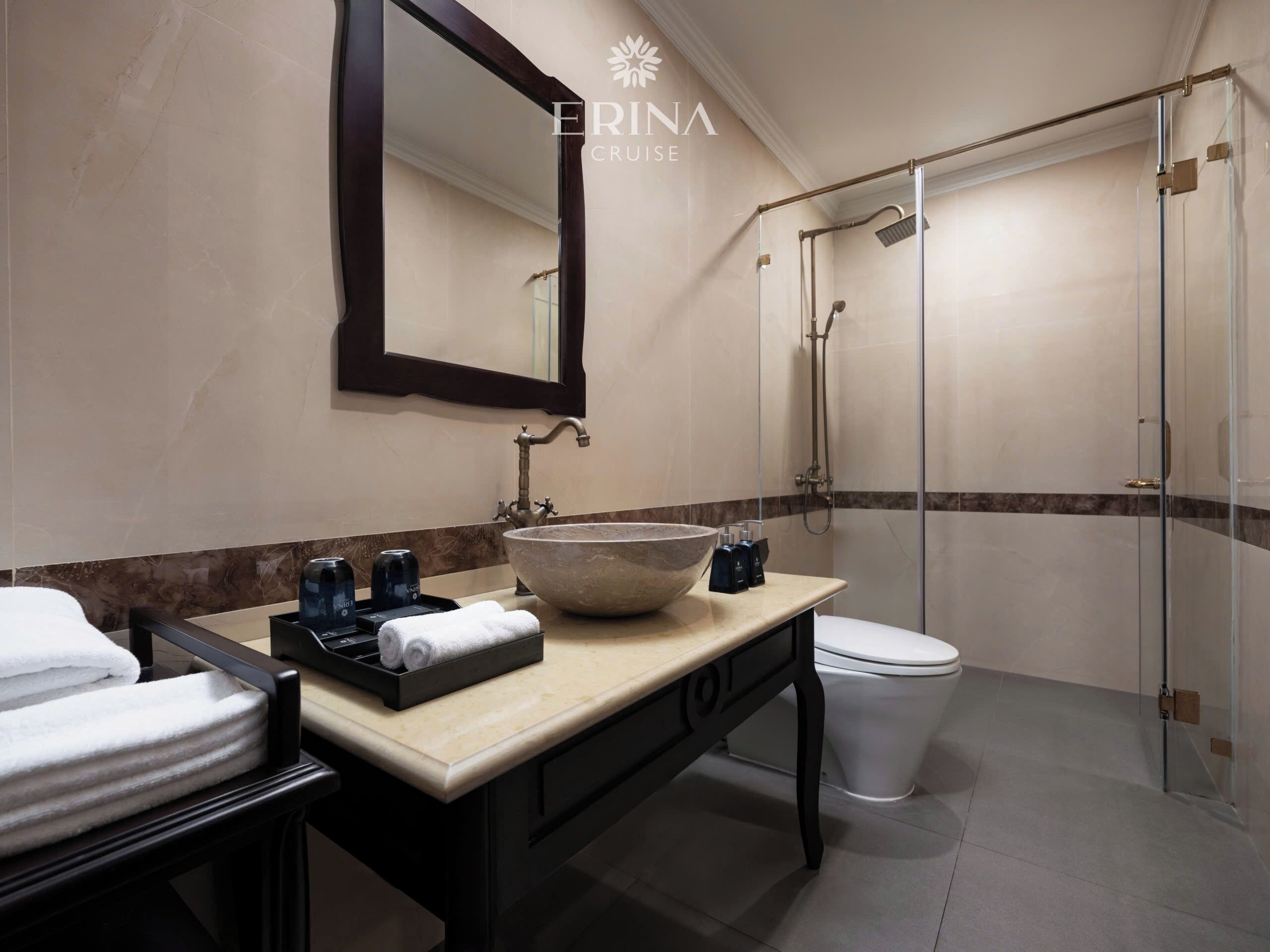 A modern bathroom with a large mirror, a vessel sink, a toilet, and a glass-enclosed shower.