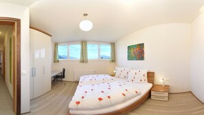 A bedroom with a bed, a desk, and a chair. There is a window with curtains, a radiator, and a painting on the wall. - Karglhof - Villa (Finkenstein am Faaker See)