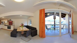 A modern kitchen with a dining area, a balcony with a view, and a sliding glass door. - Karglhof - Villa (Finkenstein am Faaker See)