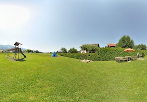 A park with a playground, picnic area, and buildings in the background.