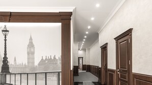 Um corredor com vista para a torre do relógio do Big Ben, painéis de madeira e piso polido.