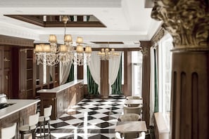 Een luxueuze hotellobby met een geruit vloerkleed, sierlijke kroonluchters en klassieke decoratie.