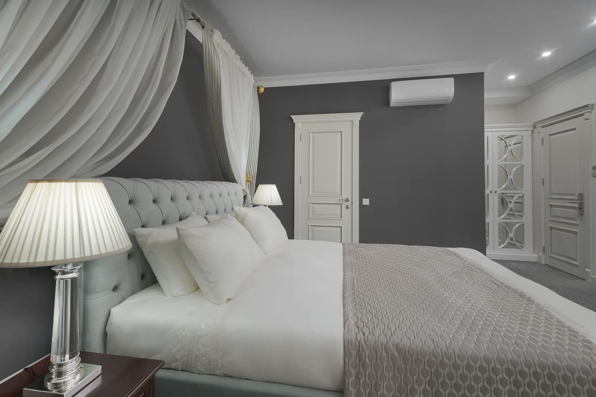 A bedroom with a large bed, two bedside lamps, a nightstand, and a wardrobe.