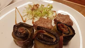 Un plato con carne enrollada y verduras, posiblemente un tipo de rollo o plato relleno, acompañado de col rallada y una pequeña cantidad de salsa.
