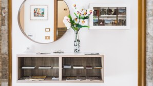 Ein modernes Zimmer mit einem runden Spiegel, einer Blumenvase und einem gerahmten Bild an der Wand.