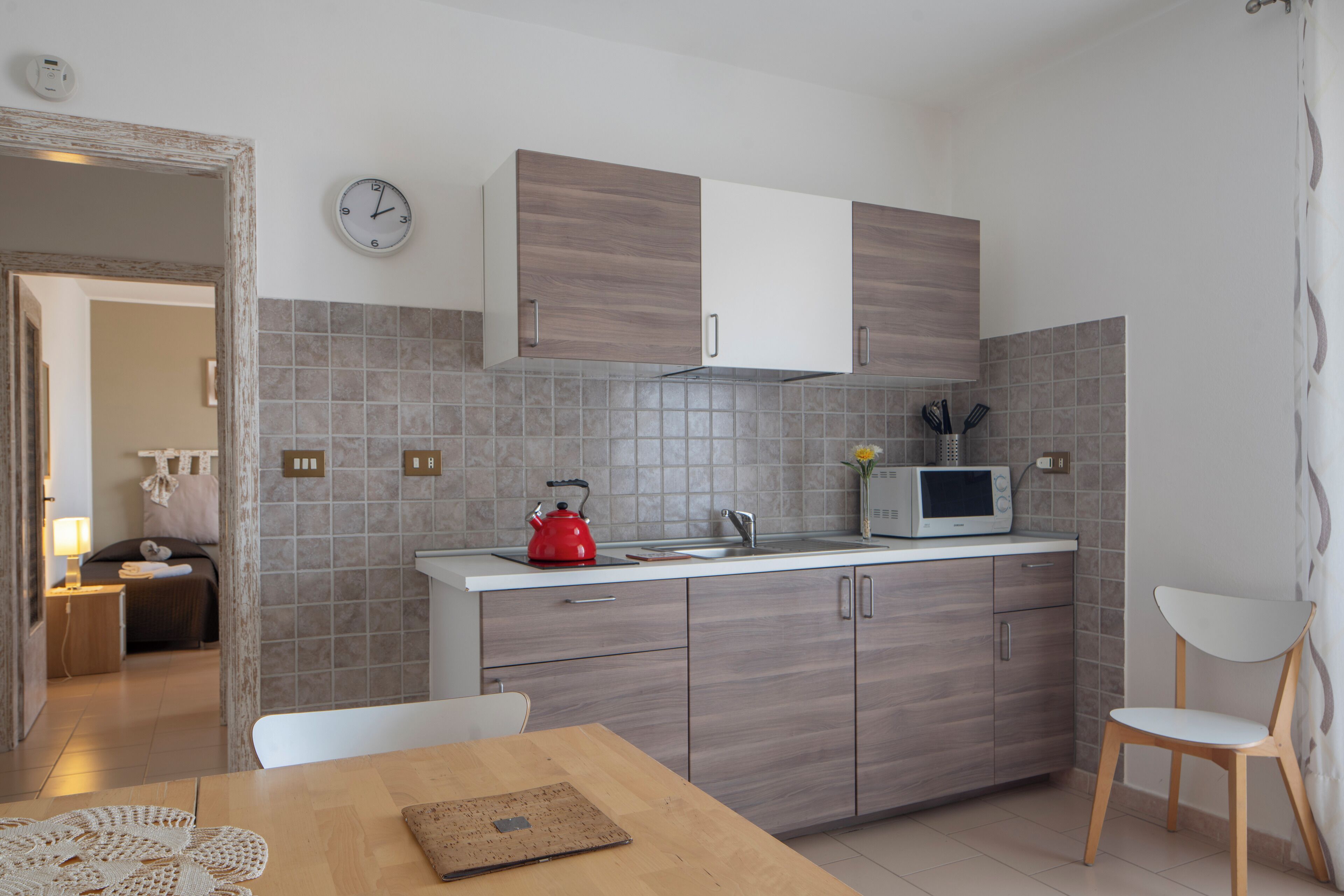 A modern kitchen with grey cabinets, a microwave, and a kettle on the counter.