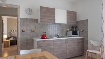 A modern kitchen with grey cabinets, a microwave, and a kettle on the counter.