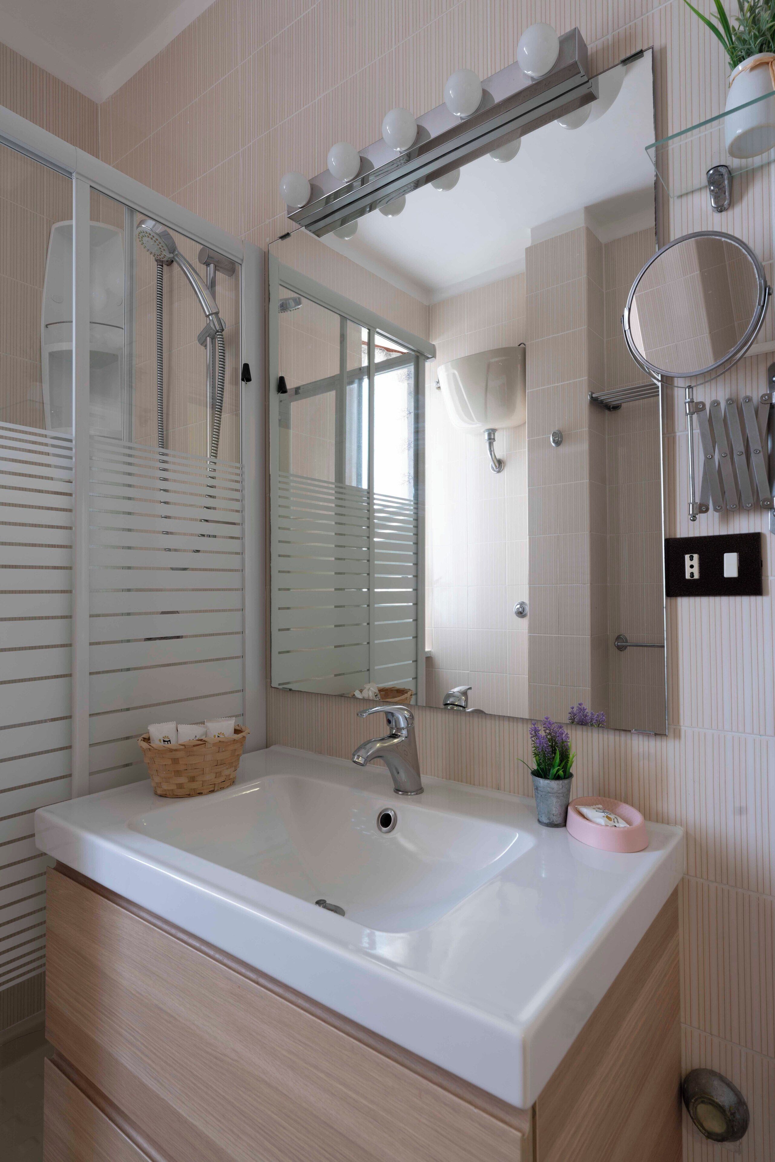 A modern bathroom with a large sink, a mirror, a shower, and a vanity with drawers.
