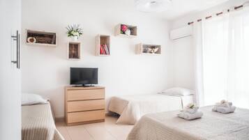Een moderne hotelkamer met twee bedden, een televisie, houten opbergmeubels en een raam met gordijnen.