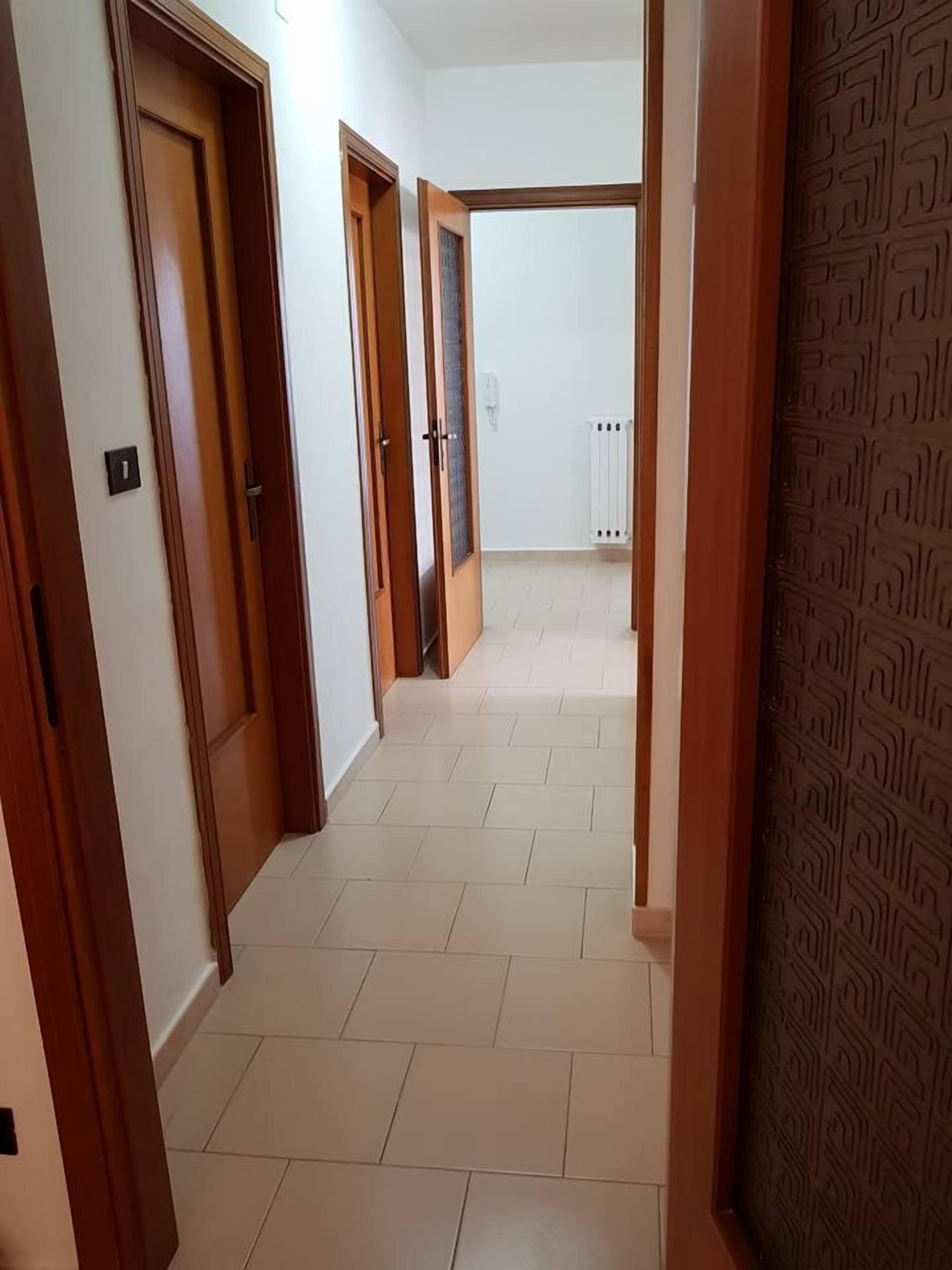 Un pasillo con puertas de madera y un radiador al fondo.