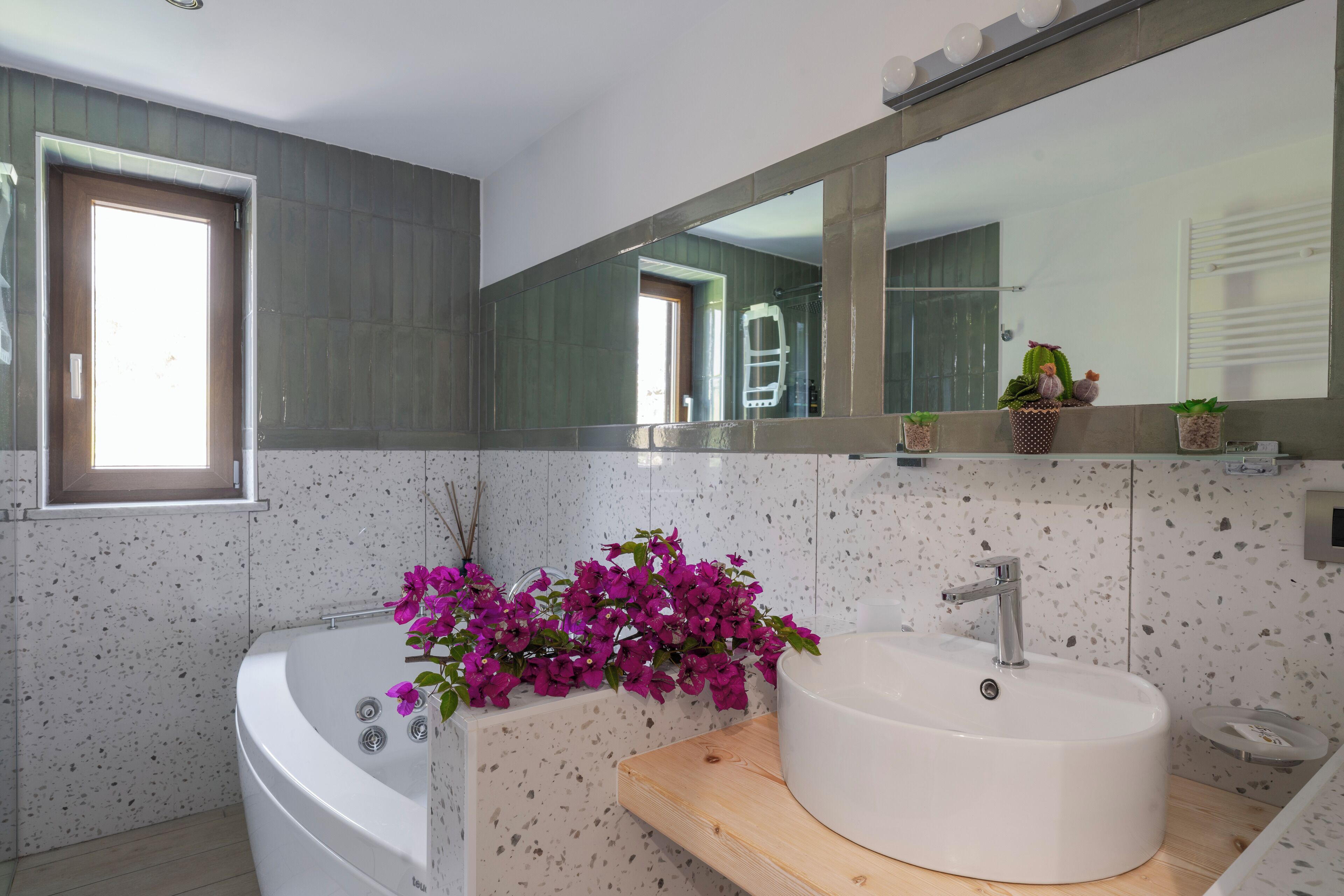Un baño moderno con una bañera independiente, un lavabo redondo y un espejo grande.