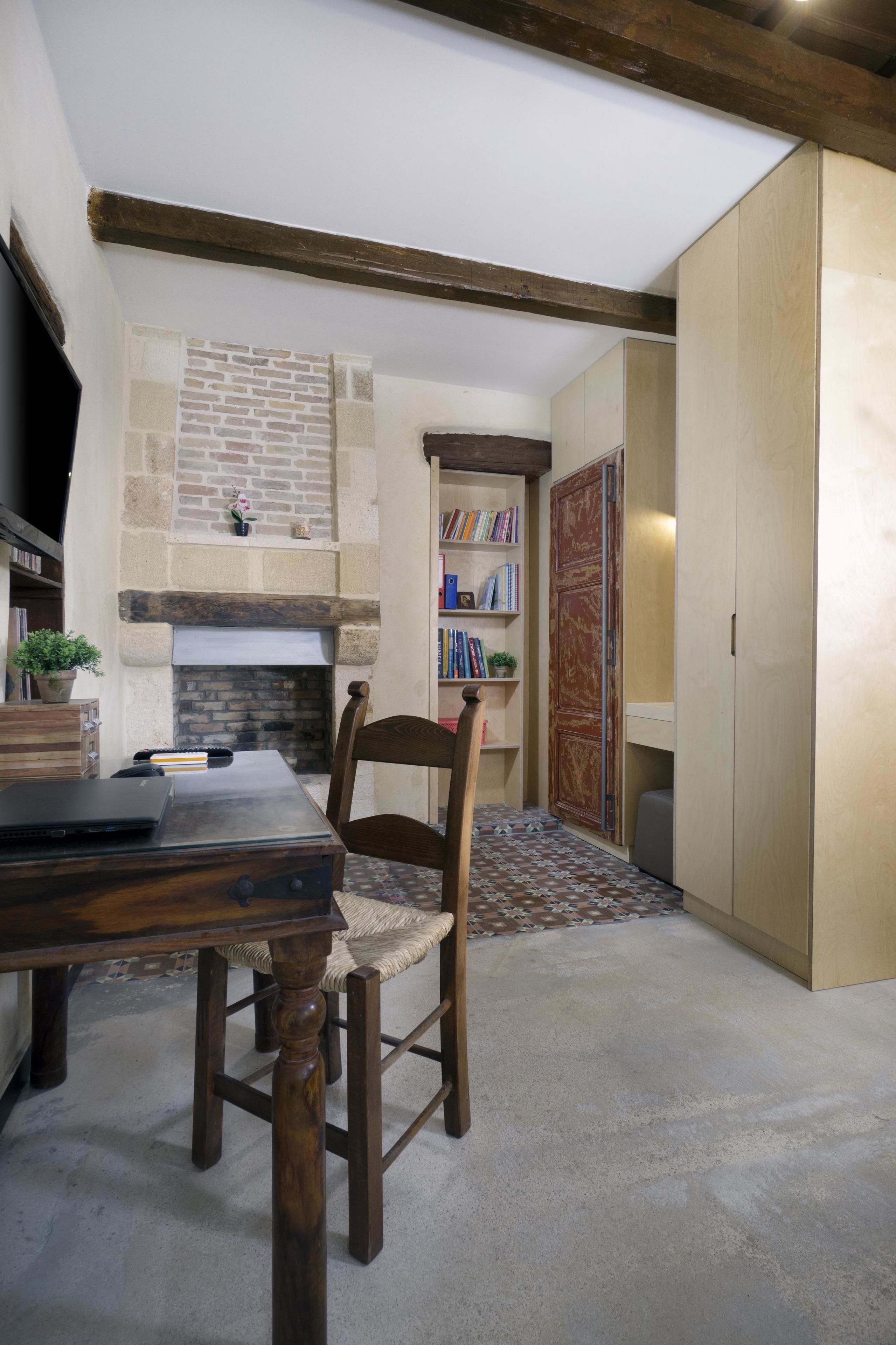 A cozy room with a fireplace, a bookshelf, and a dining area with a wooden table and chair.