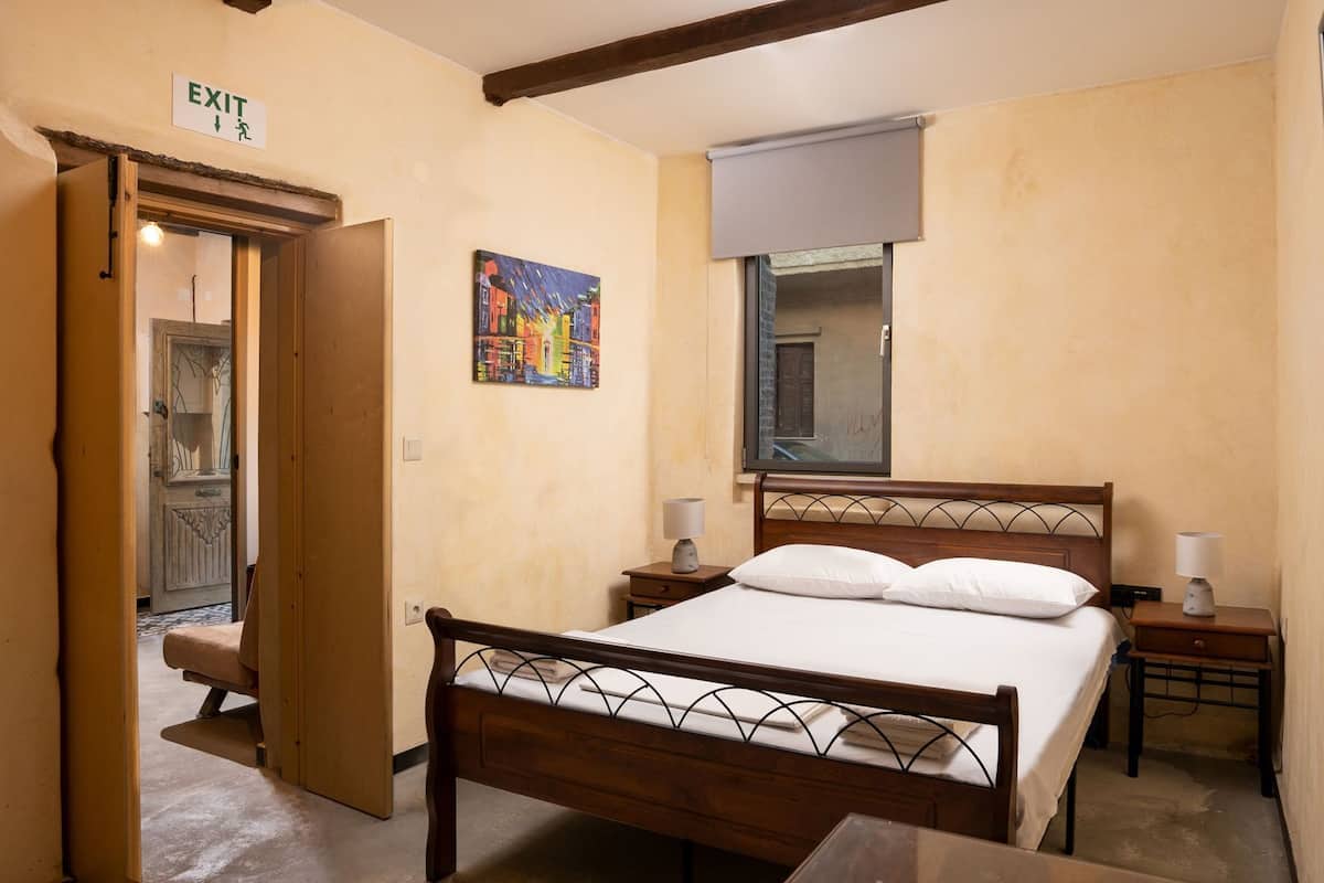 Ein Schlafzimmer mit einem hölzernen Bett, Nachttischen, einem Gemälde und einem Fluchtzeichen.