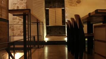 Interior de un restaurante con suelo de madera, paredes de piedra e iluminación moderna.