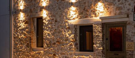 A stone building with multiple windows and doors, illuminated by exterior lighting.