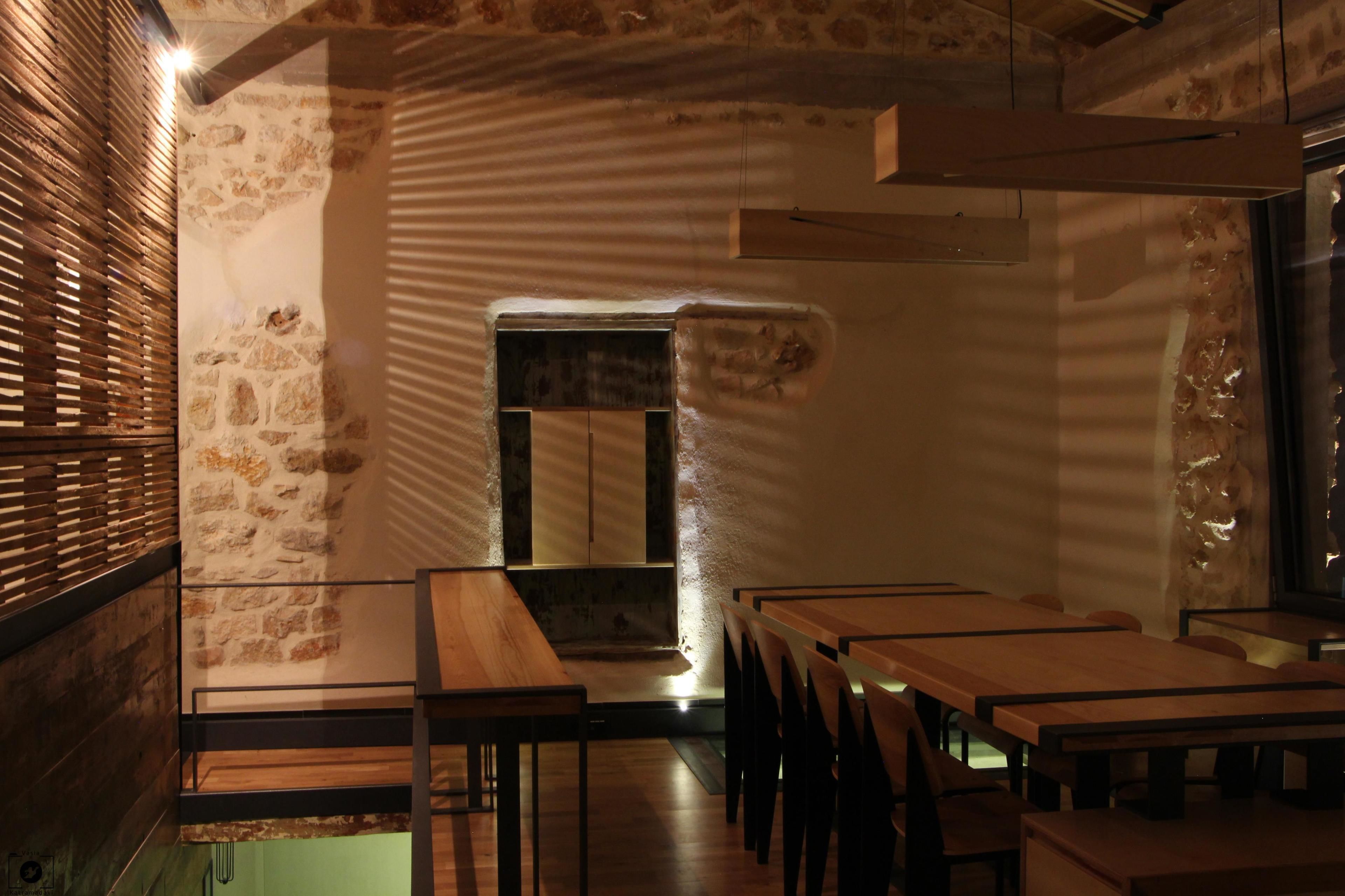 A restaurant interior with stone walls, wooden tables, and a central seating area.