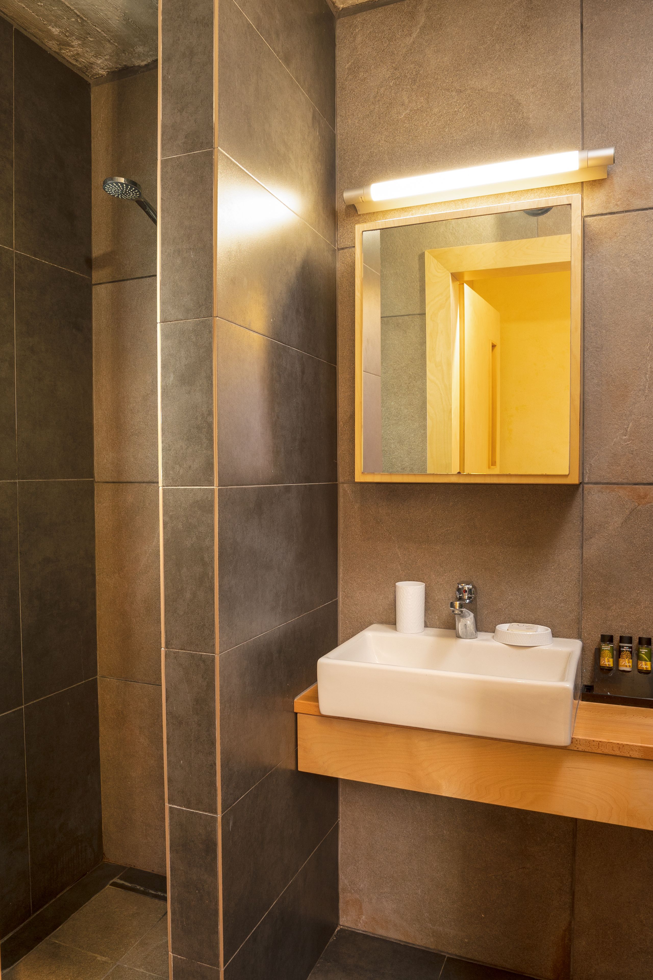 A modern bathroom with a shower, a sink with a mirror, and toiletries on the counter.