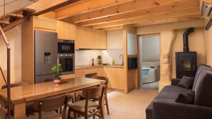 A modern kitchen with wooden cabinets, a built-in oven, and a dining area with a table and chairs. - Evans House II (Chania)