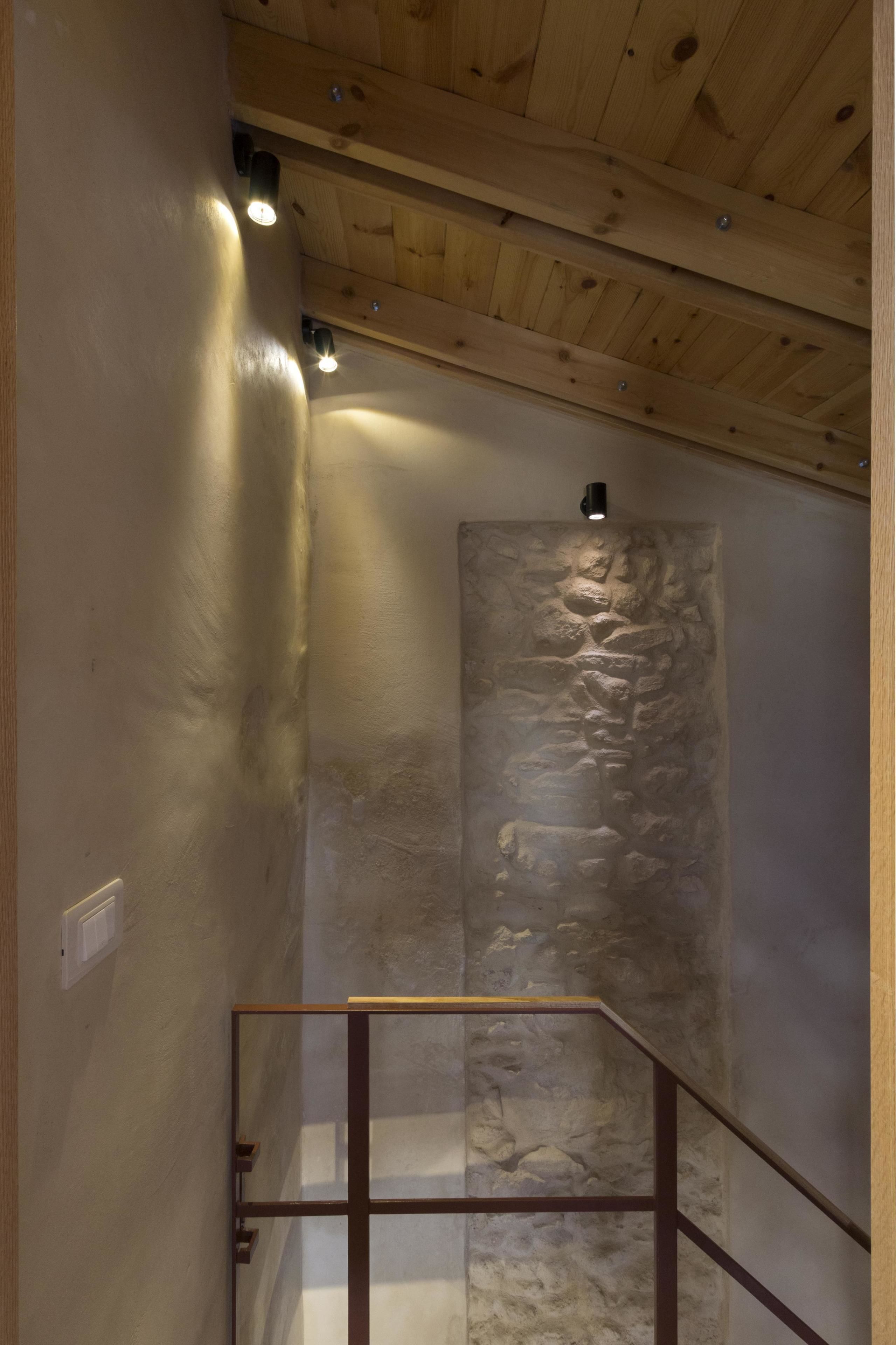 A staircase with a stone wall and wooden ceiling.