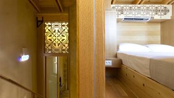 Un intérieur en bois comprenant un lit, un panneau décoratif mural et une prise électrique visible.