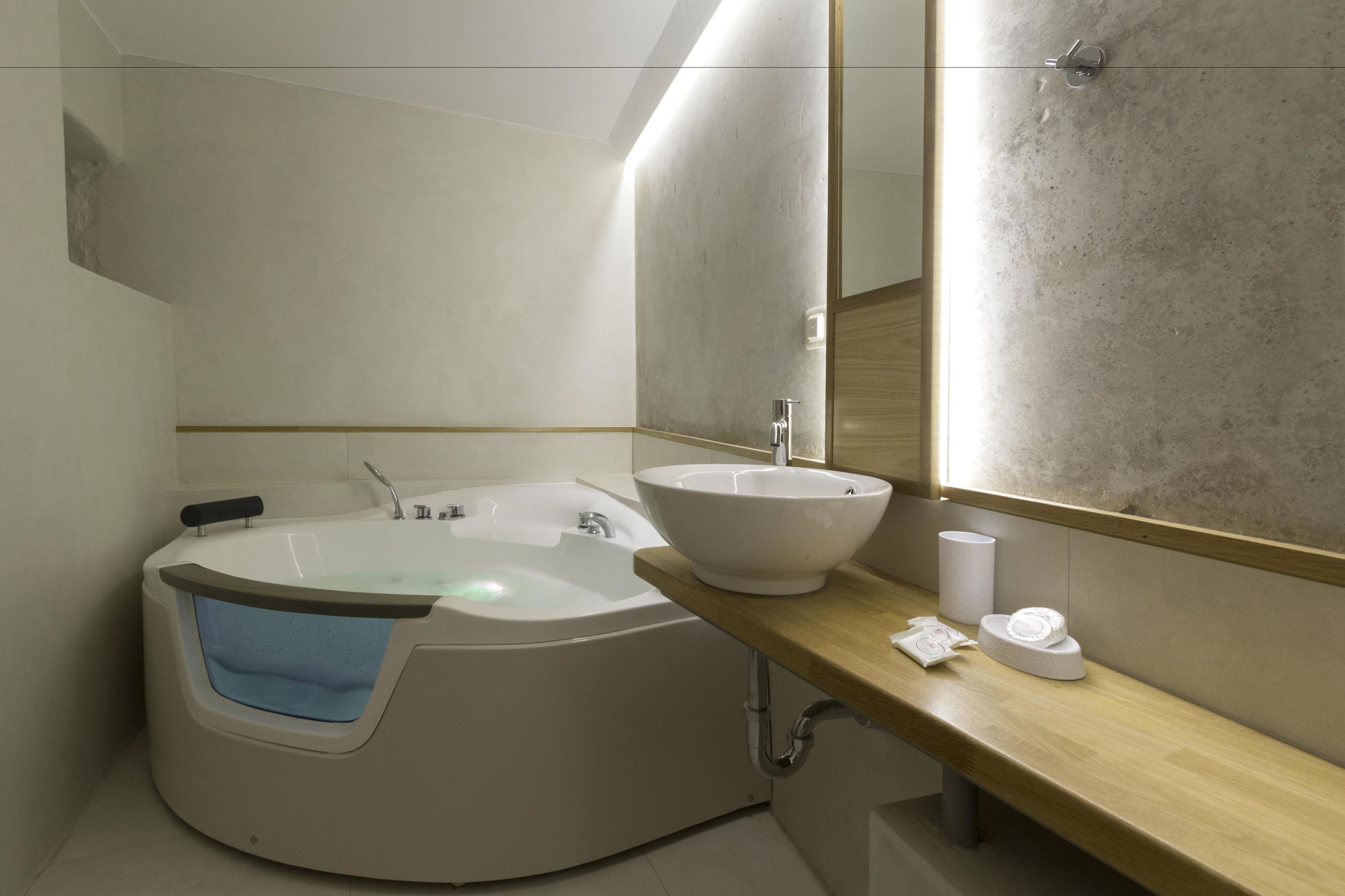 Un baño moderno con una bañera independiente, un lavamanos grande y un espejo.