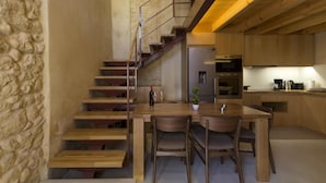 A modern kitchen with wooden cabinets, a built-in oven, and a dining area with a wooden table and chairs. - Evans House II (Chania)