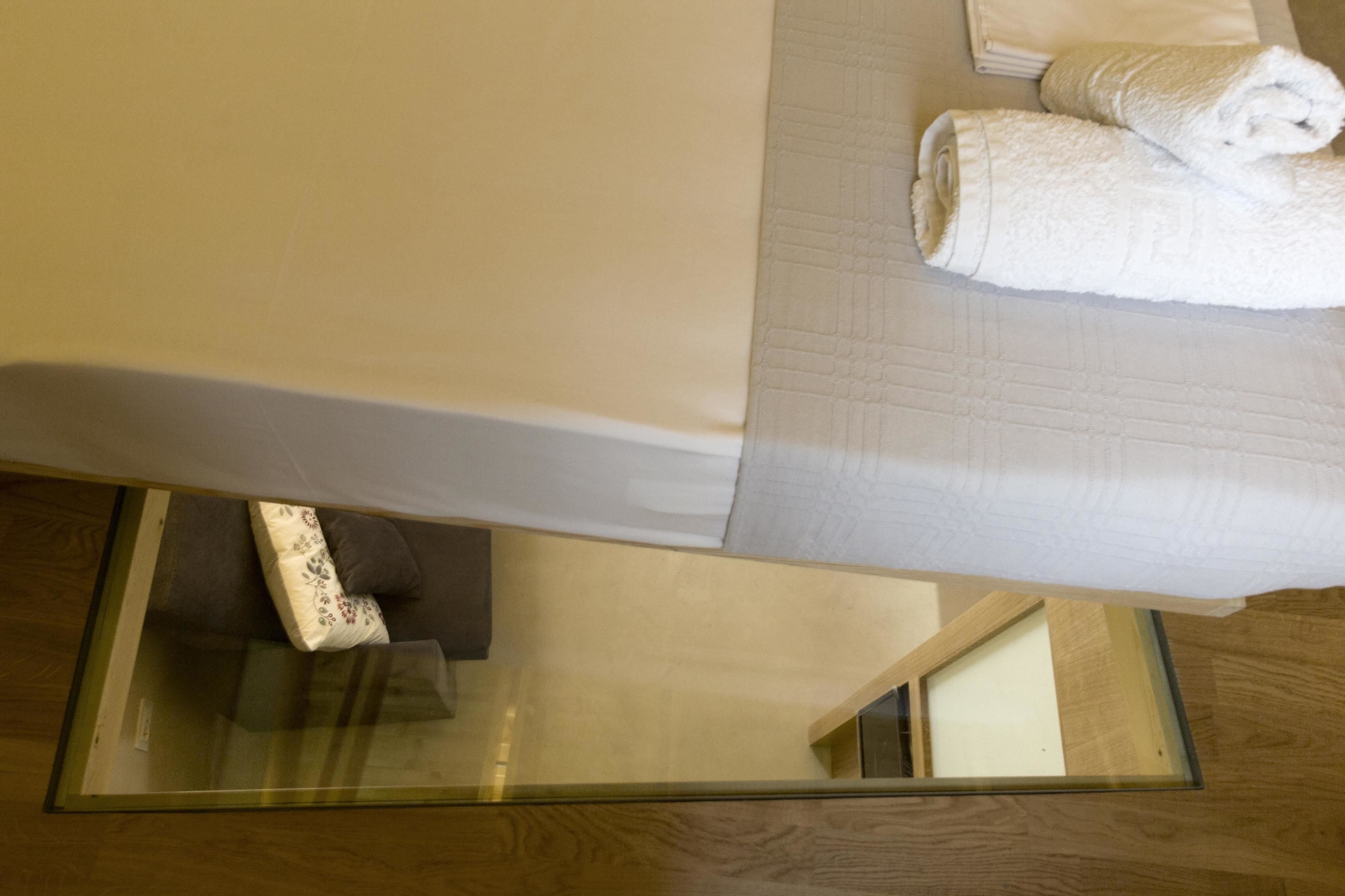 Ein Hotelzimmer mit einem Bett, einem Glastisch und Holzboden.