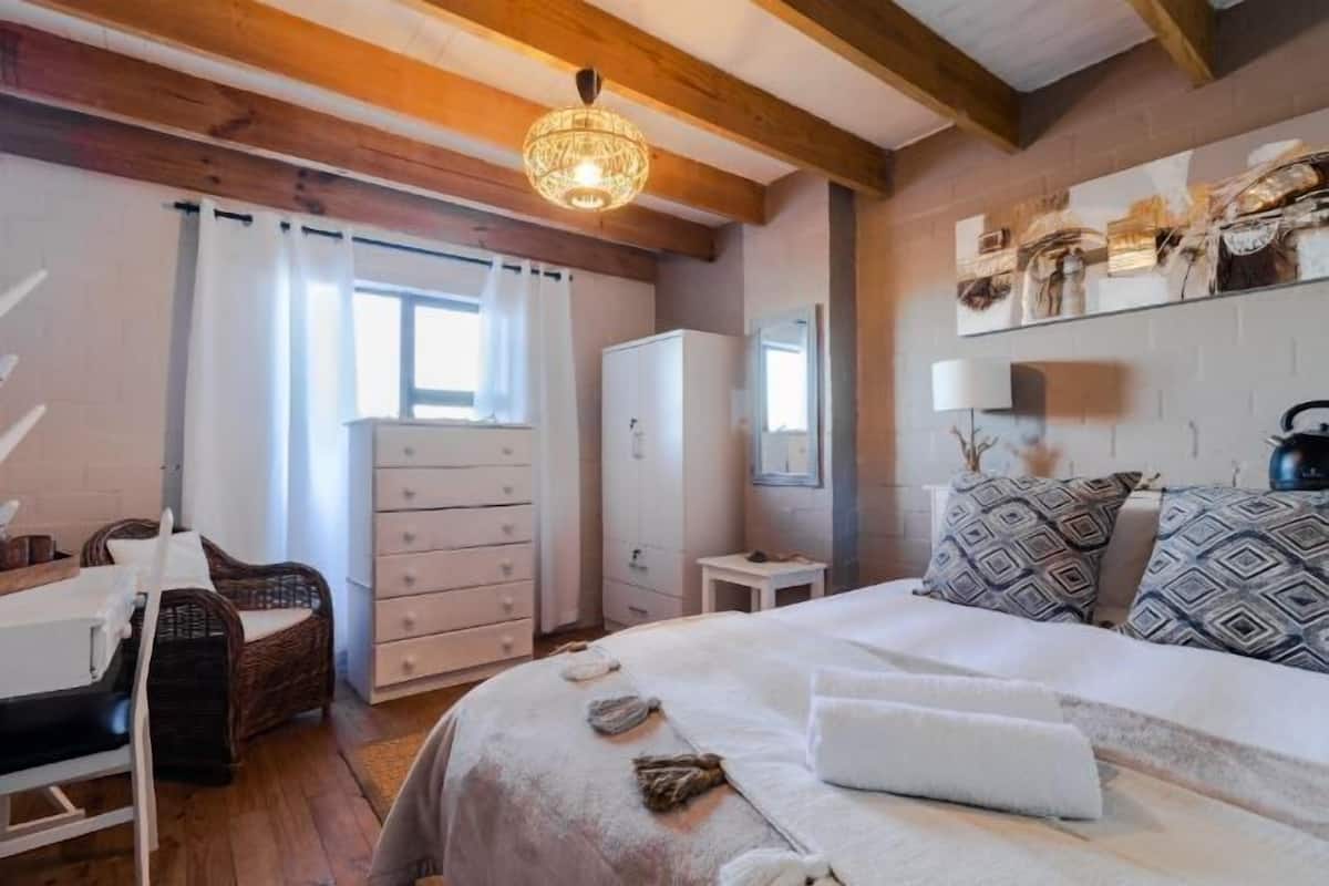 A bedroom with a bed, dresser, and a small table.