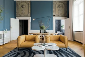 A living room with a yellow sofa, a round coffee table, and a black and white striped rug.
