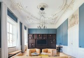 A spacious living room with a large TV, comfortable seating, and decorative ceiling details.