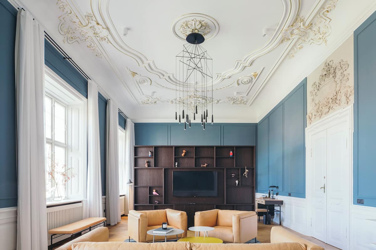 Un salon spacieux doté d’un grand téléviseur, de sièges confortables et de détails décoratifs au plafond.