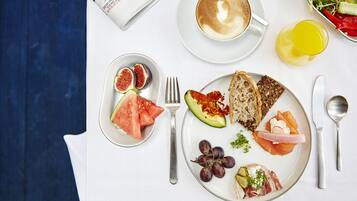 A breakfast setting with a newspaper, a cup of coffee, and various food items on a table.