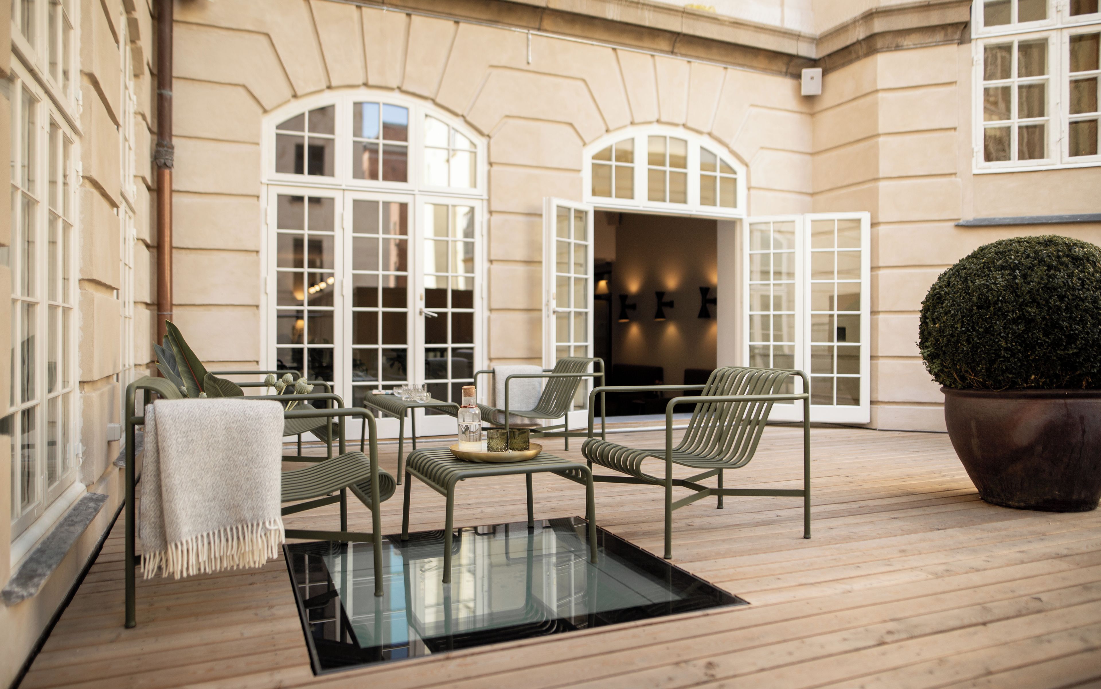 A wooden deck with outdoor seating, large windows, and a potted plant.