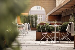 An outdoor patio area with tables and chairs, a small round table, and a potted plant.
