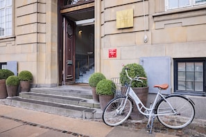 A building entrance with a wooden door, a sign for Nobis Hotel, and a bicycle parked outside.