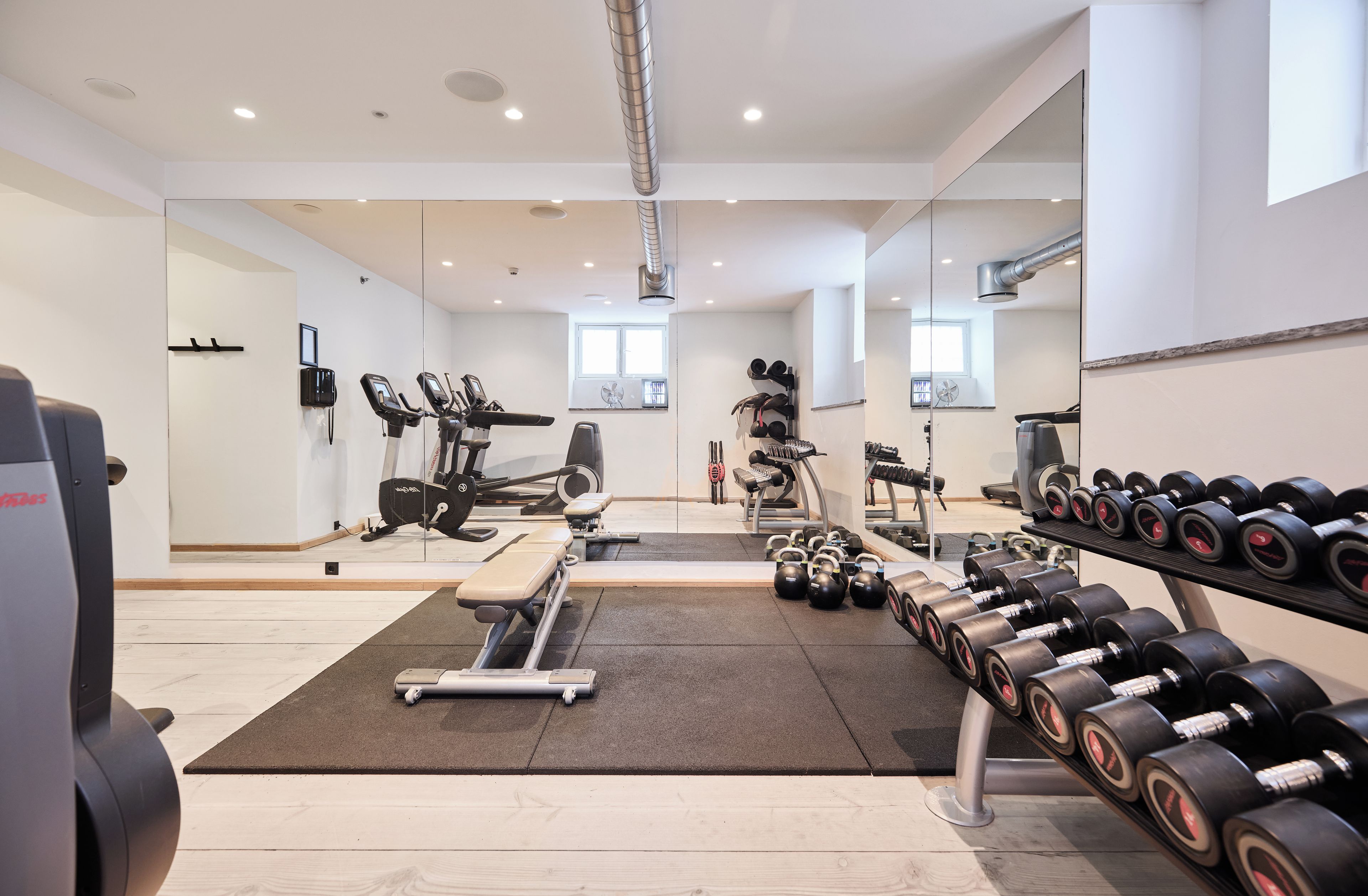 A gym with exercise equipment, mirrors, and a variety of weights.